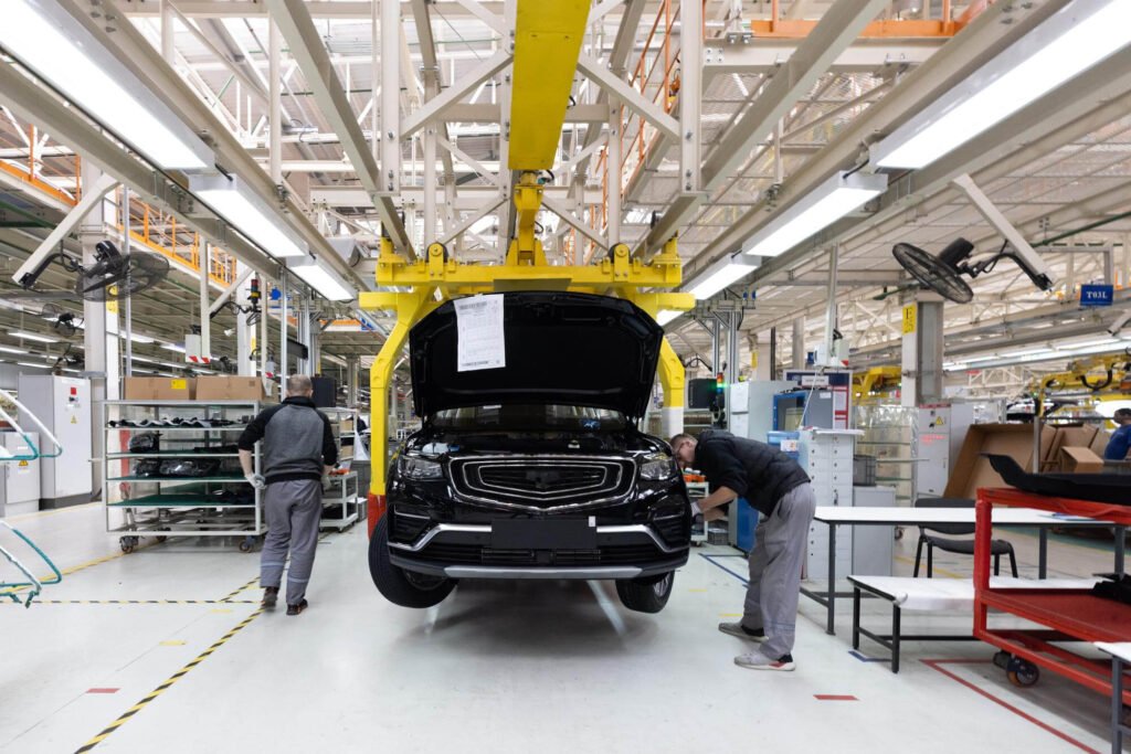 2 personas en una línea de producción automotriz, ensamblando un automóvil negro | Imagen desde freepik, por usertrmk